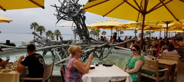 Seaside cafe seating with umbrellas and modern art fountain sculpture